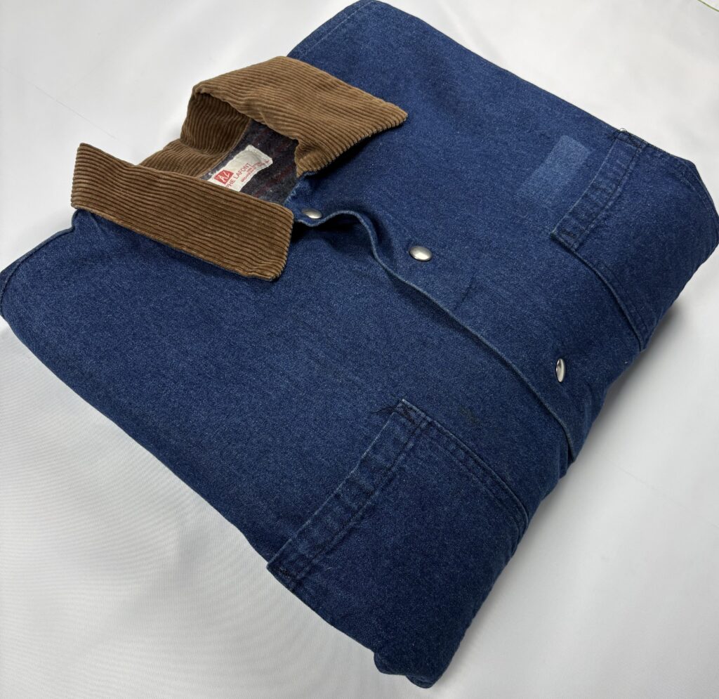 Folded vintage Adolphe Lafont blue denim work jacket showing the brown corduroy collar, metal snaps and chest pockets.